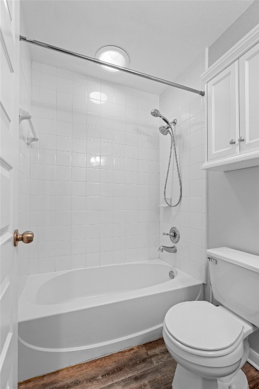 bathroom featuring toilet, tiled shower / bath, and wood-type flooring