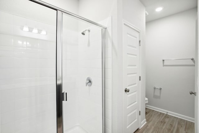 bathroom with toilet, an enclosed shower, and hardwood / wood-style floors