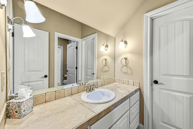 bathroom featuring vanity, toilet, and lofted ceiling