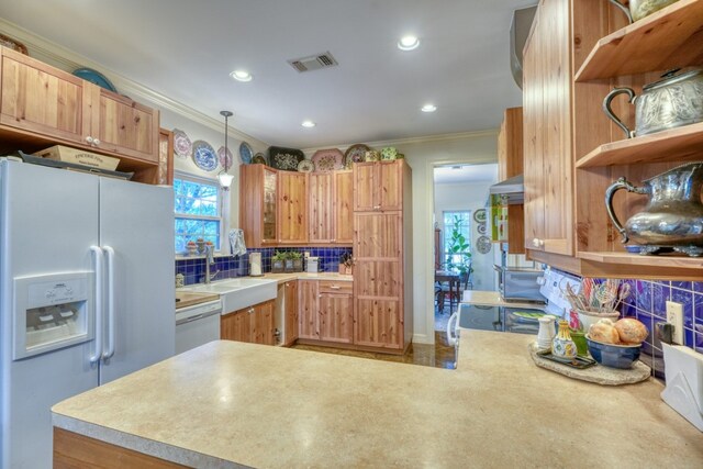 kitchen with ornamental molding, pendant lighting, sink, decorative backsplash, and white appliances