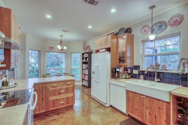 kitchen featuring a wealth of natural light, white appliances, sink, and hanging light fixtures