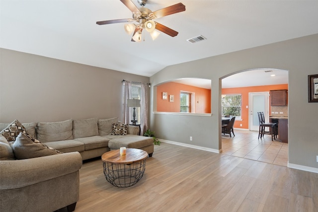 living room with ceiling fan, vaulted ceiling, and light wood-type flooring