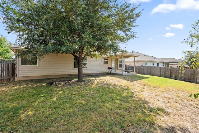 rear view of property featuring a yard and a patio area