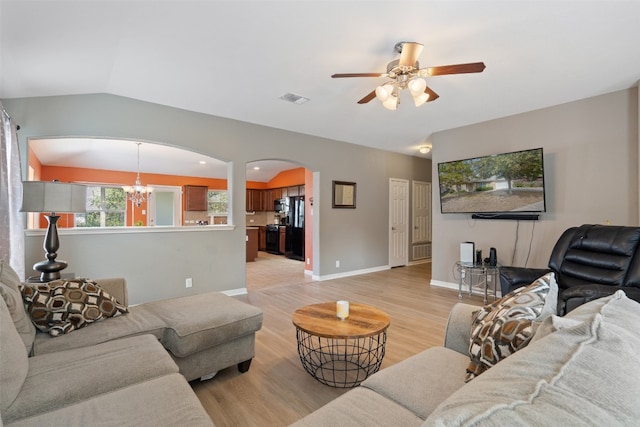 living room with vaulted ceiling, ceiling fan with notable chandelier, and light hardwood / wood-style floors