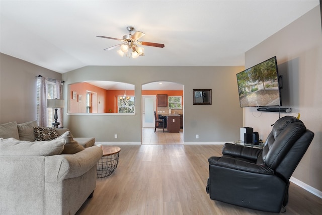 living room featuring light hardwood / wood-style floors, ceiling fan with notable chandelier, and vaulted ceiling