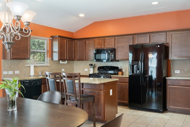 kitchen featuring lofted ceiling, backsplash, light stone countertops, black appliances, and a center island