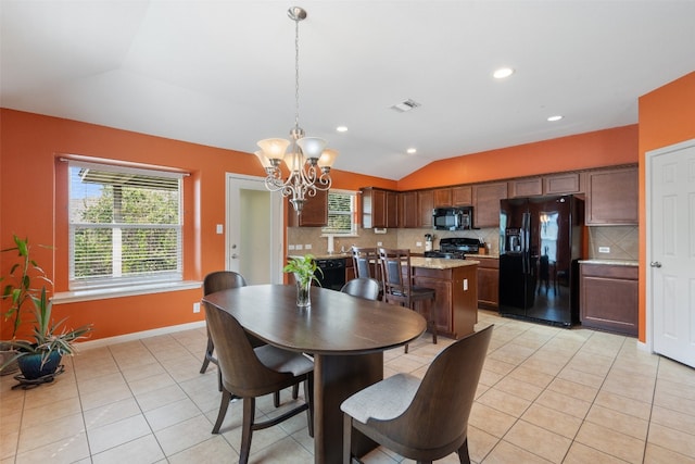 tiled dining room featuring an inviting chandelier and vaulted ceiling