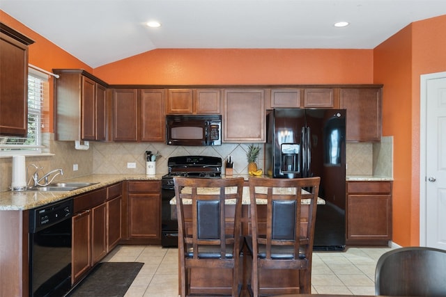 kitchen featuring lofted ceiling, backsplash, sink, black appliances, and light stone countertops