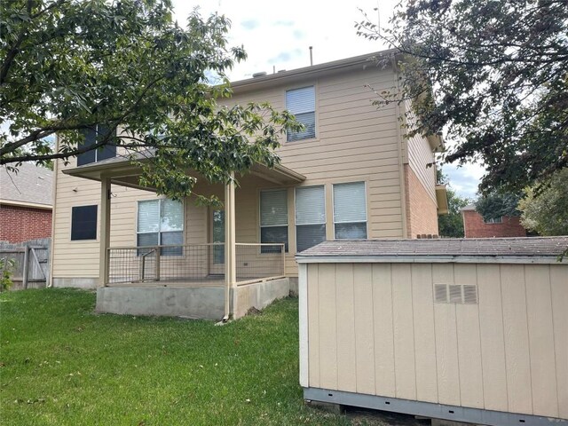 rear view of property featuring covered porch and a yard