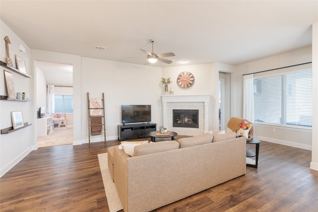 living room with ceiling fan, a tiled fireplace, and dark hardwood / wood-style flooring