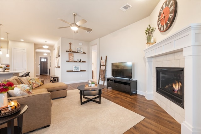 living room with hardwood / wood-style floors, a tiled fireplace, and ceiling fan