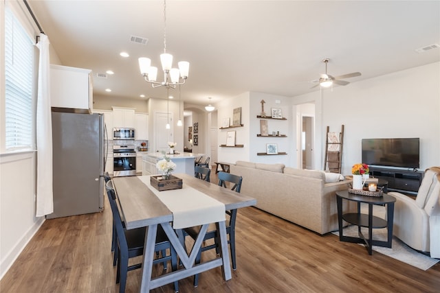 dining space with hardwood / wood-style floors and ceiling fan with notable chandelier