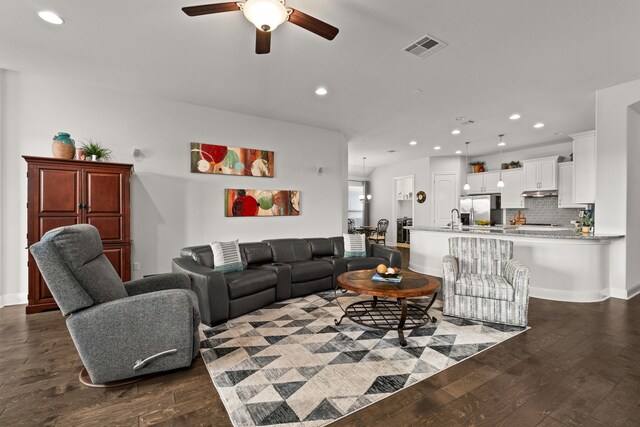 living room featuring ceiling fan and dark hardwood / wood-style floors