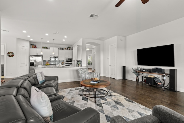 living room with ceiling fan and dark hardwood / wood-style flooring