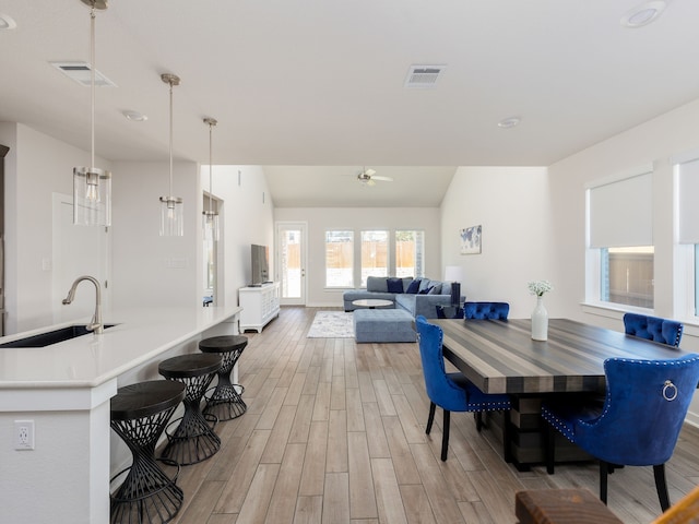 dining space featuring sink, vaulted ceiling, hardwood / wood-style floors, and ceiling fan