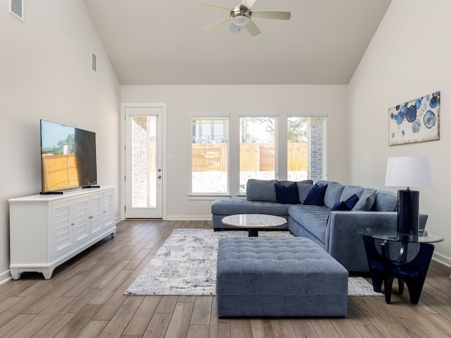 living room with ceiling fan, high vaulted ceiling, and light wood-type flooring