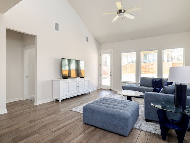 living room with ceiling fan, high vaulted ceiling, and light hardwood / wood-style flooring