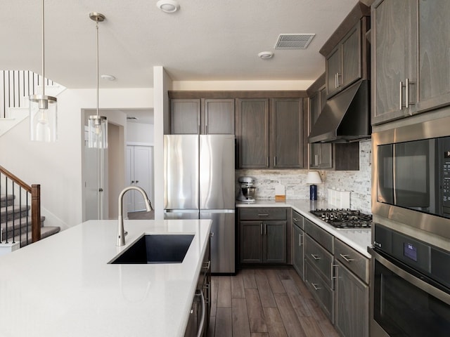 kitchen featuring sink, backsplash, hanging light fixtures, exhaust hood, and stainless steel appliances