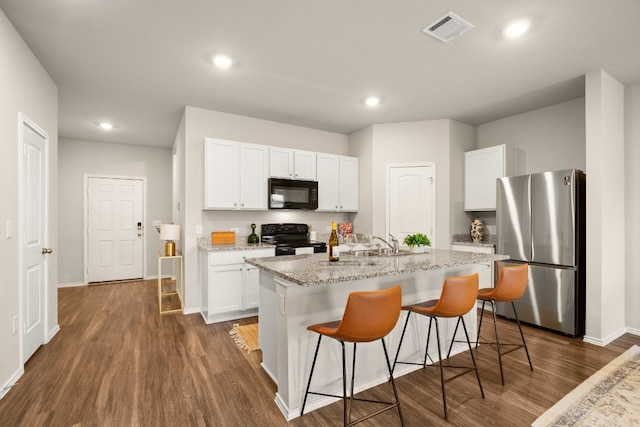 kitchen with a kitchen island with sink, dark wood-type flooring, sink, black appliances, and white cabinetry