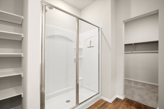 bathroom with a shower with door and wood-type flooring