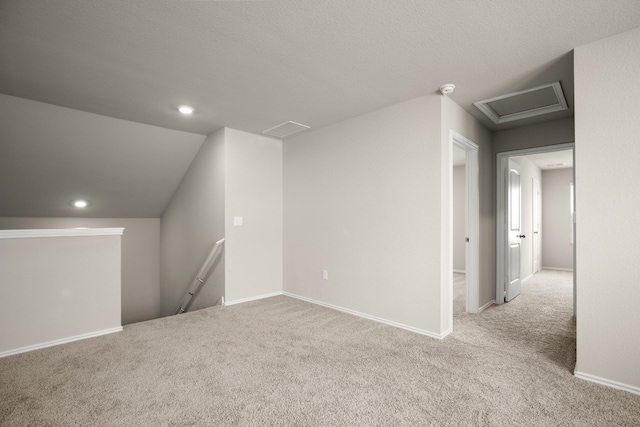 additional living space with lofted ceiling, a textured ceiling, and light colored carpet