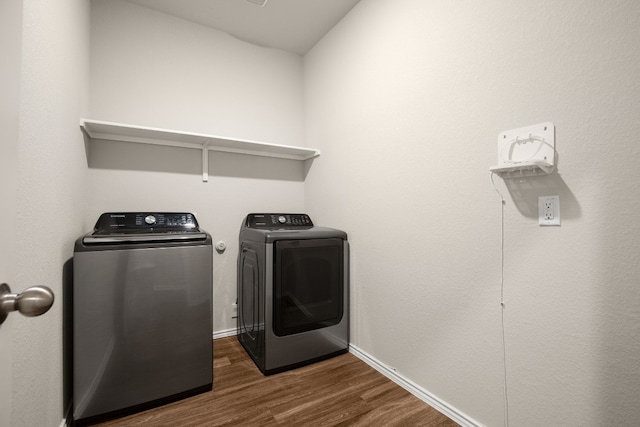 clothes washing area with washing machine and dryer and dark hardwood / wood-style flooring