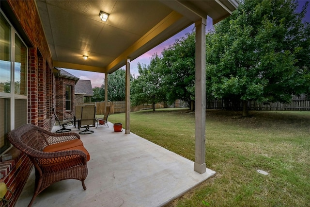 patio terrace at dusk featuring a yard