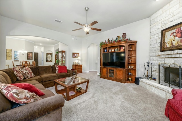 living room with carpet flooring, ceiling fan with notable chandelier, and a stone fireplace