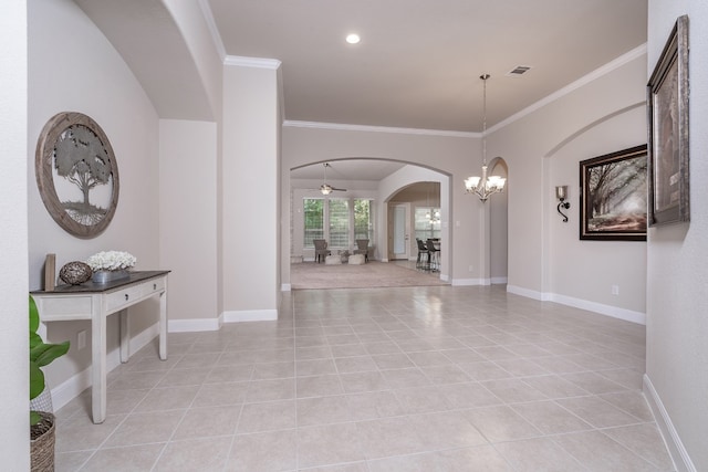 entryway featuring ceiling fan with notable chandelier, light tile patterned flooring, and crown molding