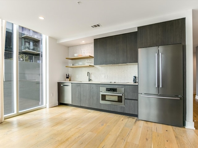 kitchen featuring backsplash, sink, appliances with stainless steel finishes, and light wood-type flooring