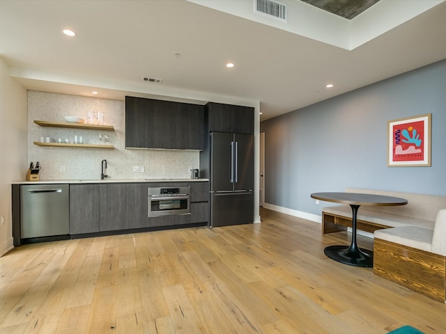 kitchen featuring light hardwood / wood-style floors, appliances with stainless steel finishes, sink, and backsplash