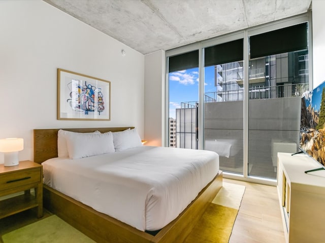 bedroom with light hardwood / wood-style floors, access to outside, and floor to ceiling windows