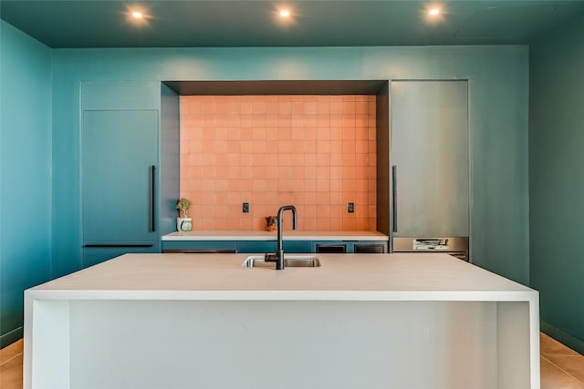 kitchen with light tile patterned floors, sink, and a center island with sink