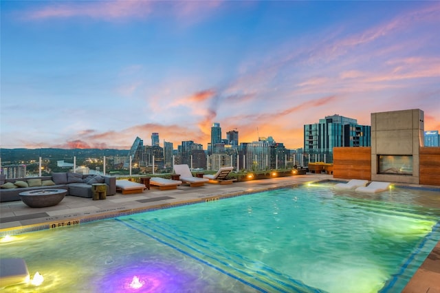 pool at dusk with an outdoor fire pit and a patio area