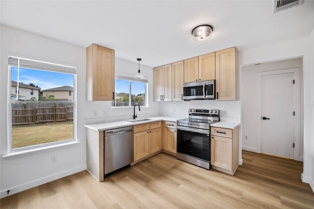 kitchen featuring appliances with stainless steel finishes, light hardwood / wood-style flooring, pendant lighting, and light brown cabinets