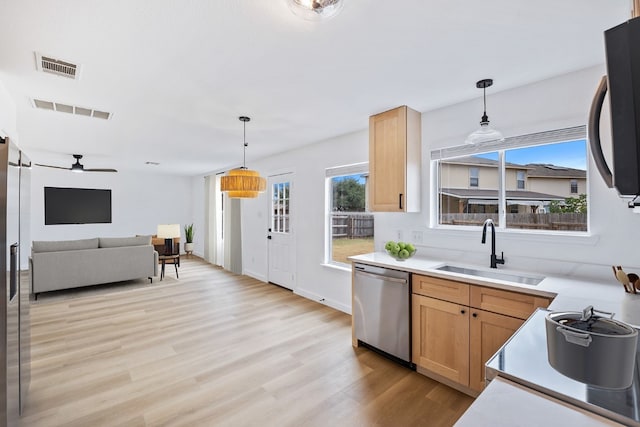 kitchen with stainless steel dishwasher, light brown cabinetry, light wood-type flooring, pendant lighting, and sink