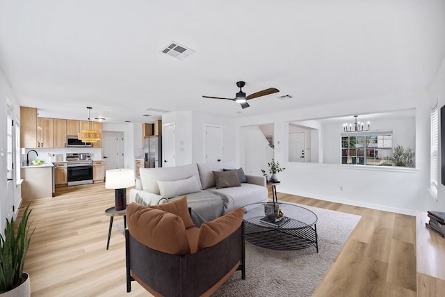 living room featuring sink, ceiling fan with notable chandelier, and light wood-type flooring