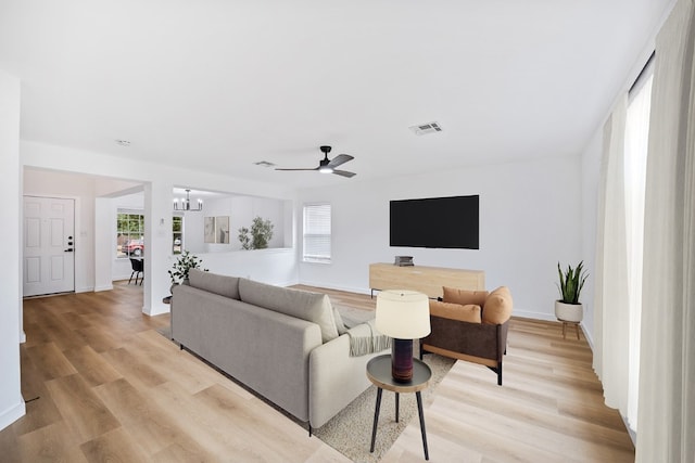 living room featuring light hardwood / wood-style floors and ceiling fan with notable chandelier