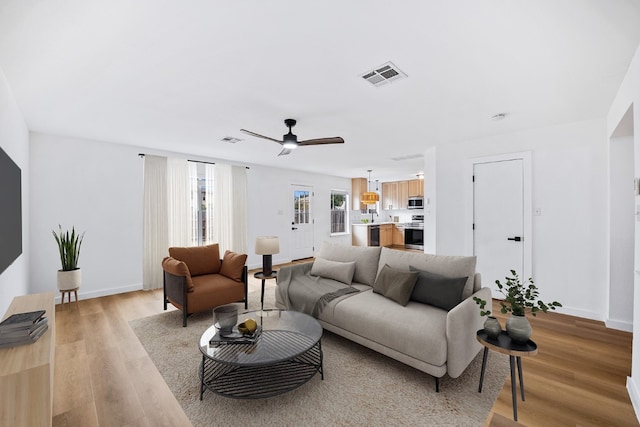 living room with light hardwood / wood-style floors and ceiling fan