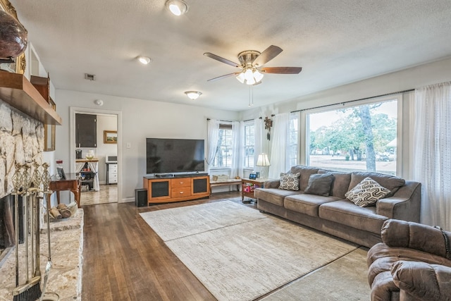 living room featuring ceiling fan, a textured ceiling, and dark hardwood / wood-style flooring