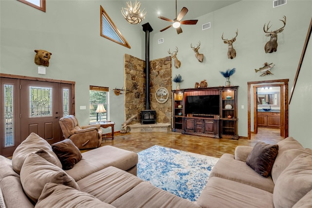 living room with a high ceiling, a wood stove, and ceiling fan