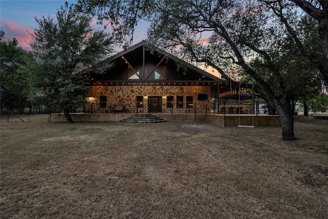 back house at dusk featuring a lawn