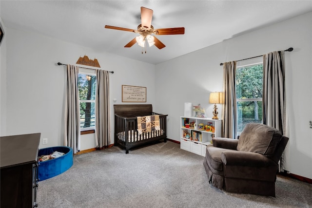 bedroom featuring carpet, a nursery area, multiple windows, and ceiling fan