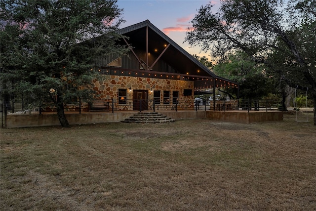 back house at dusk featuring a lawn