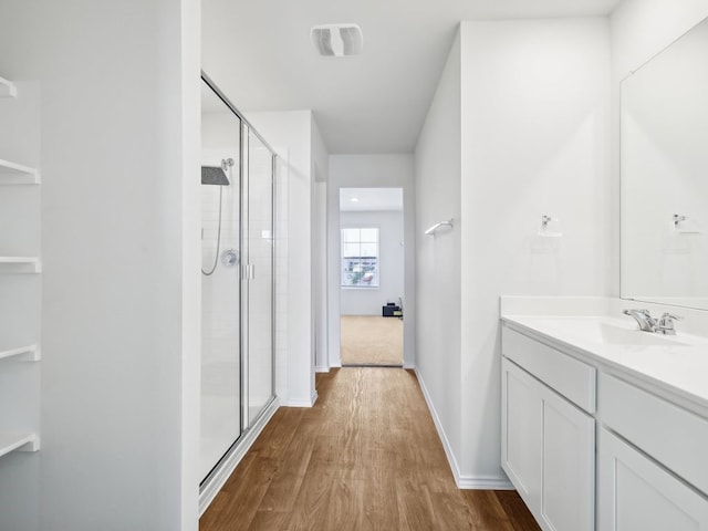 bathroom with hardwood / wood-style floors, vanity, and a shower with door