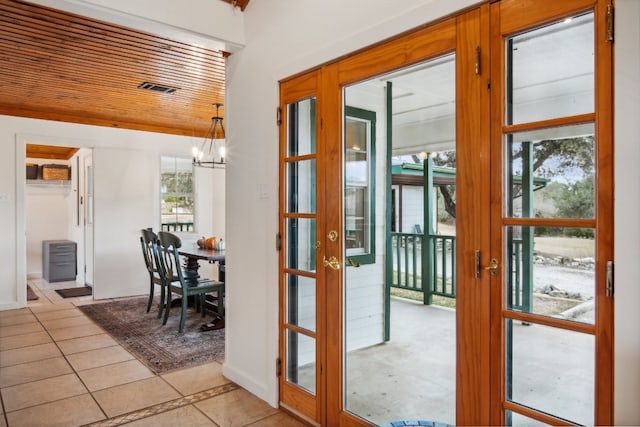 doorway featuring an inviting chandelier, french doors, wood ceiling, and light tile patterned floors