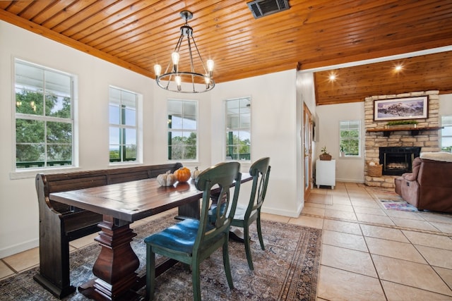 dining area with a stone fireplace, wood ceiling, a chandelier, and light tile patterned floors