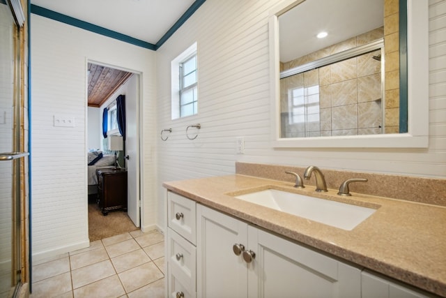 bathroom with vanity, crown molding, a shower with shower door, and tile patterned flooring