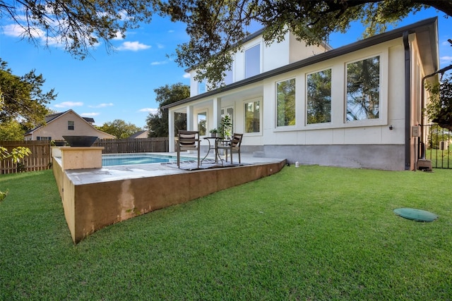 back of property featuring an outdoor kitchen, a patio area, a yard, and a fenced in pool