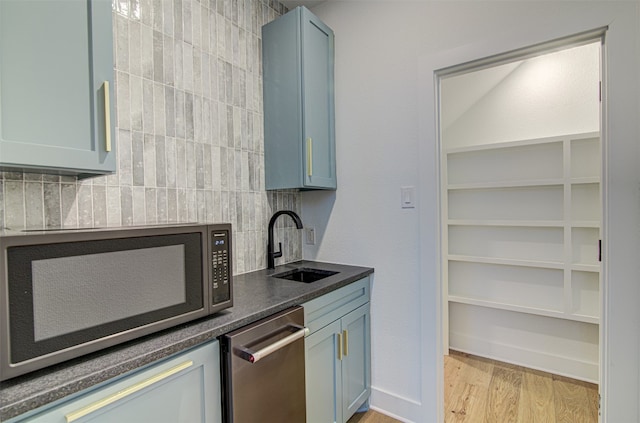 kitchen with decorative backsplash, light hardwood / wood-style floors, blue cabinets, and sink